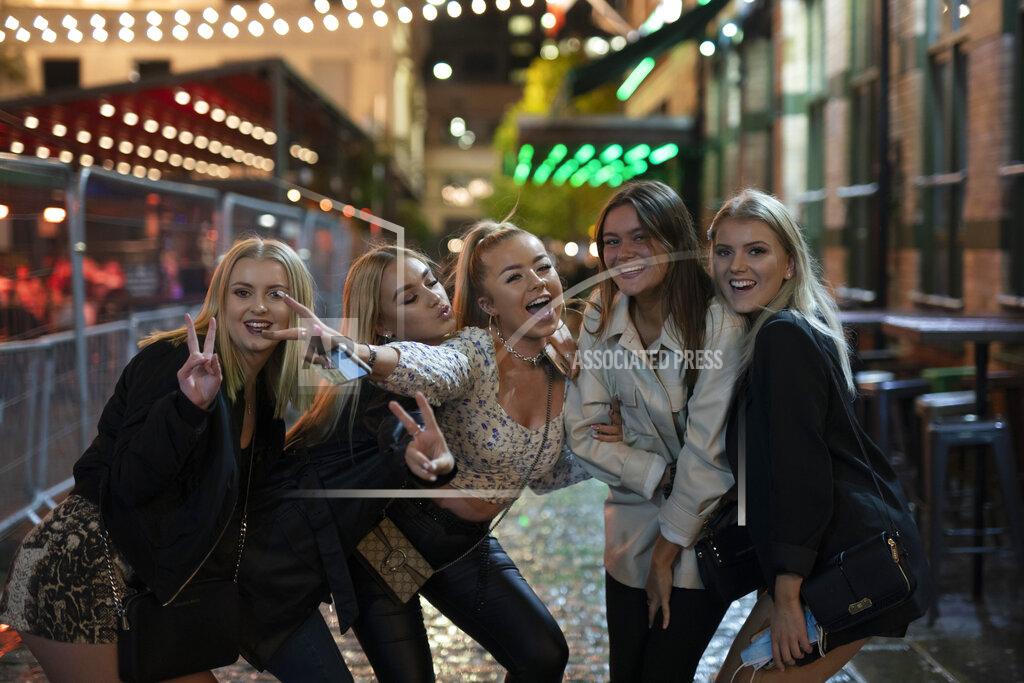 Jon Super Young people pose for a photo, outside a bar in Liverpool, England, Monday Oct. 12, 2020. The English port city that gave the world the Beatles weathered decades of industrial decline before becoming a celebrated symbol of urban renewal. Liverpool made itself vibrant again by promoting local culture, soccer and ties to the Fab Four. But past government neglect left Liverpudlians with mistrust of London politicians, and the virus pandemic has brought it to the surface. (AP Photo/Jon Super)