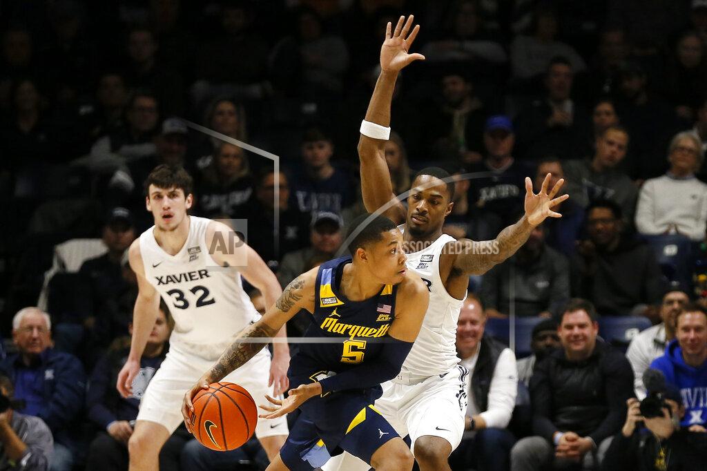 Sam Greene Marquette guard Greg Elliott (5) passes away from Xavier guard Nate Johnson, right, in the first half of an NCAA college basketball game at Cintas Center in Cincinnati on Saturday, Dec. 18, 2021. (Sam Greene/The Cincinnati Enquirer via AP)