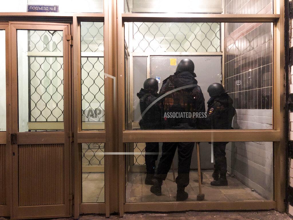 Mstyslav Chernov Police stand in front of a door of the apartment building where Oleg Navalny, brother of jailed opposition leader Alexei Navalny lives in Moscow, Russia, Wednesday, Jan. 27, 2021. Police are searching the Moscow apartment of jailed Russian opposition leader Alexei Navalny, another apartment where his wife is living and two offices of his anti-corruption organization. Navalny's aides reported the Wednesday raids on social media. (AP Photo/Mstyslav Chernov)