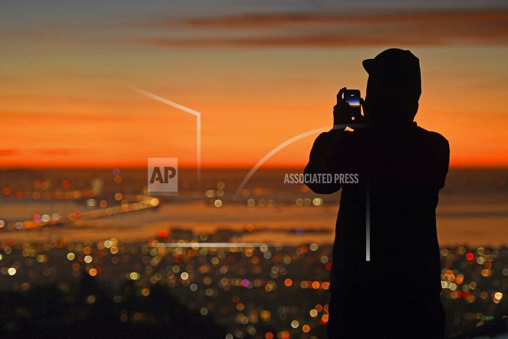 Jose Carlos Fajardo A person stops to take a picture of the sun setting behind the San Francisco skyline as seen from Grizzly Peak Boulevard in Oakland, Calif., Thursday, Dec. 31, 2020. (Jose Carlos Fajardo/Bay Area News Group via AP)