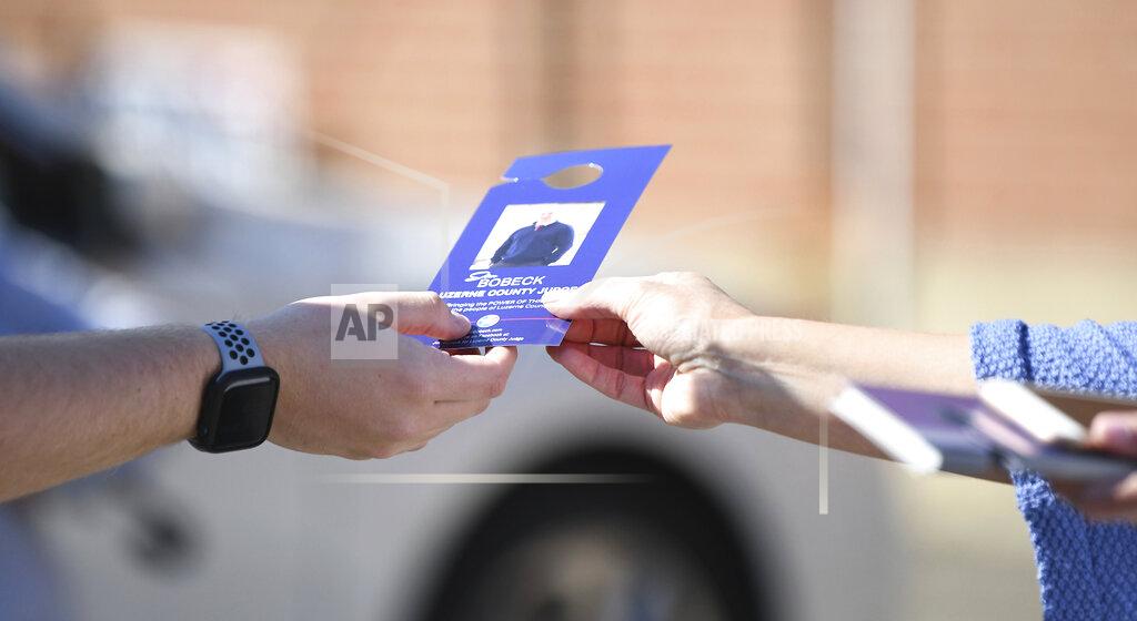 Mark Moran A poll worker, right, hands a candidate information placard to an arriving voter for the primary election at St. Monica Parish, West Wyoming, Pa., on Tuesday, May 18, 2021. (Mark Moran/The Citizens' Voice via AP)