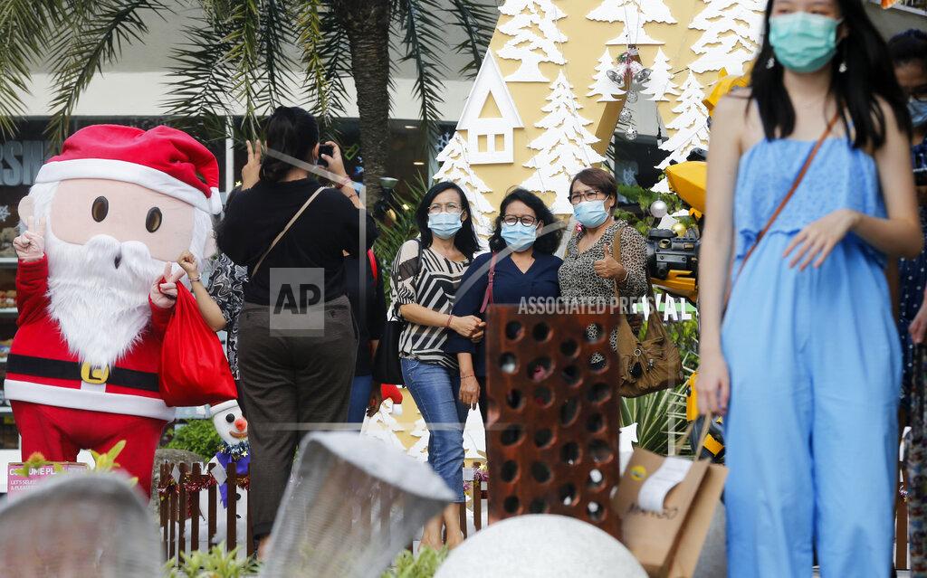 Firdia Lisnawati Women wearing masks to help curb the spread of the coronavirus pose for a photo with Santa in Bali, Indonesia on Tuesday, Dec. 22, 2020. Indonesia has reported more than 600,000 cases of the coronavirus. (AP Photo/Firdia Lisnawati)
