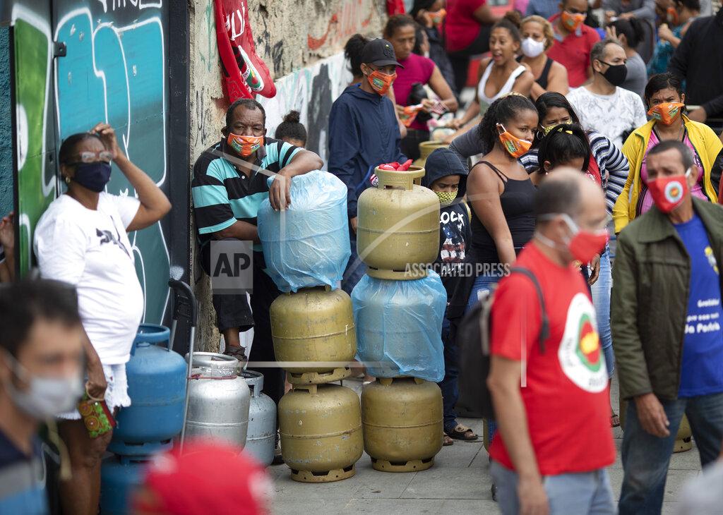 Silvia Izquierdo FILE - In this April 29, 2021 file photo, people wearing masks amid the COVID-19 pandemic wait to buy cooking gas from the Petrobras Oil Tankers Union, part of a solidarity campaign to sell fuel at low prices, in Rio de Janeiro, Brazil. The withdrawal of generous pandemic welfare payments is fueling a rapid rise in poverty in Brazil. (AP Photo/Silvia Izquierdo, File)