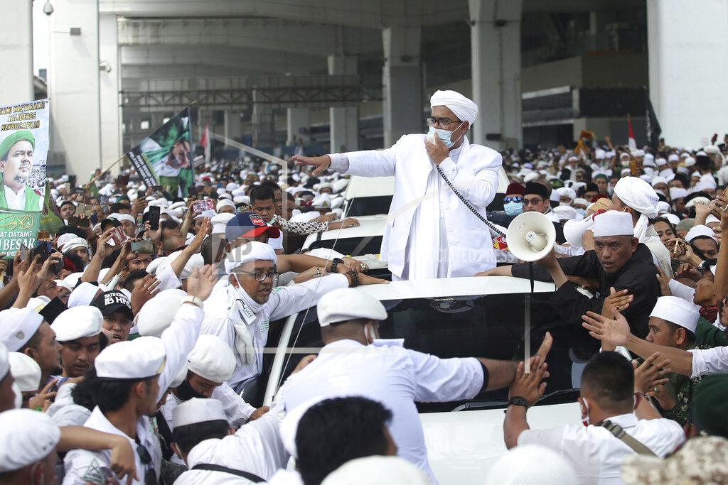 Indonesian Islamic cleric and the leader of Islamic Defenders Front Rizieq Shihab, center, speaks to his followers upon arrival from Saudi Arabia at Soekarno-Hatta International Airport in Tangerang, Indonesia, Tuesday, Nov. 10, 2020. Thousands of followers of the firebrand cleric joyfully welcomed him at an the airport as he returned home from a 3-year exile in Saudi Arabia after criminal charges including a pornography case were dropped. (AP Photo)