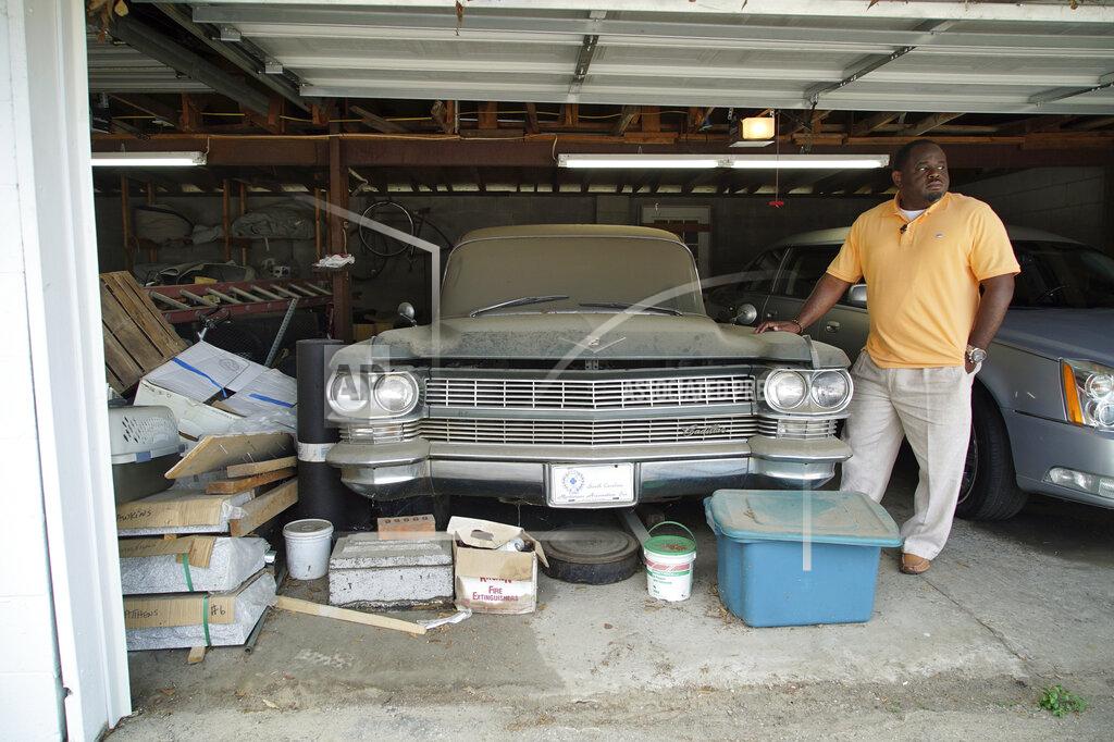 Allen G. Breed Shawn Troy stands beside the first hearse ever owned by his late father behind the family's funeral home in Mullins, S.C., on Saturday, May 22, 2021. William Penn Troy Sr. died of COVID-19 in August 2020, one of many Black morticians to succumb during the pandemic. (AP Photo/Allen G. Breed)