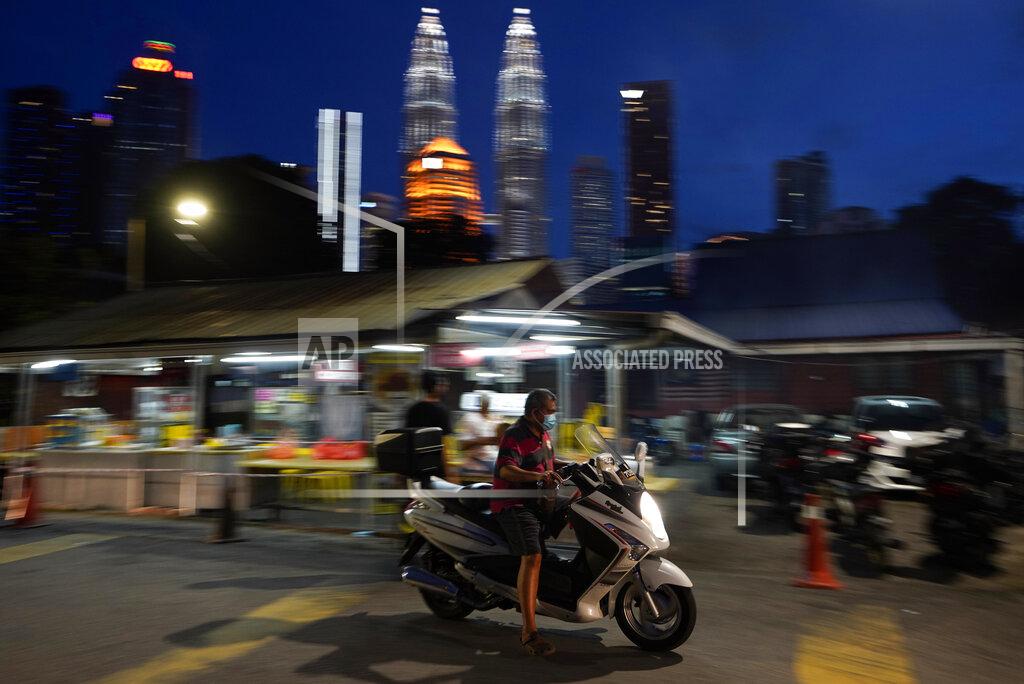 Vincent Thian A motorcyclist wears a face mask with the background of Twin Towers in downtown Kuala Lumpur, Malaysia, Monday, Jan. 11, 2021. Prime Minister Muhyiddin Yassin says Malaysia's health care system is at a breaking point as he announced new movement curbs, including near-lockdown in Kuala Lumpur and several high-risk states to rein in a spike in coronavirus cases.(AP Photo/Vincent Thian)