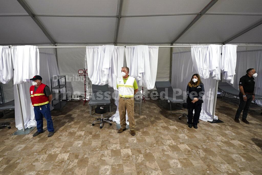 Medical professionals wait by empty beds during a tour of the new Harris County Non-Congregate Medical Shelter at NRG Park Saturday, April 11, 2020, in Houston. The new temporary setup will have 250 beds initially with a capacity of 2000 beds, if needed, to help relieve pressure on the hospital system from COVID-19 patients. Activation is not intended at this time. (AP Photo/David J. Phillip)
