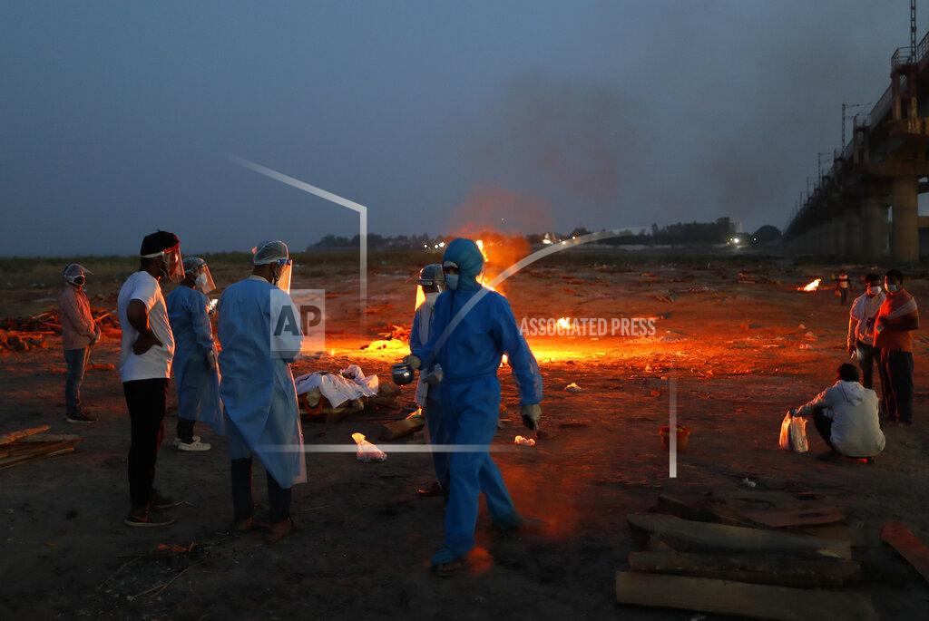 Rajesh Kumar Singh Relatives stand near the funeral pyre of their loved one who died due to COVID-19 at a cremation ground in Prayagraj, India, Saturday, May 8, 2021. (AP Photo/Rajesh Kumar Singh)