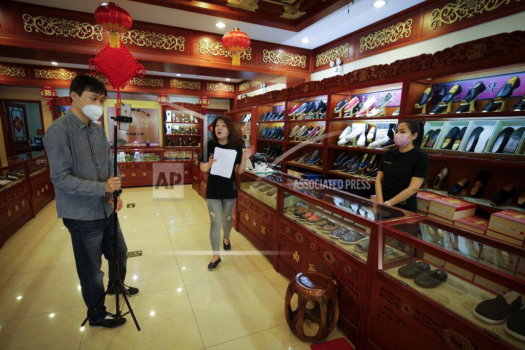 Andy Wong FILE - In this April 28, 2020, photo, Cheng Xu, center, shows her footwear for her online clients through the live-streaming at the Neiliansheng Footwear in Beijing. Livestream selling, already popular in China, is taking off in the U.S., ushering in a new way for Americans to shop online. Instead of searching for what they want, they pick up their phones, sit back, and click to buy if they like what they see. (AP Photo/Andy Wong)