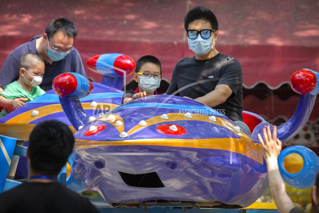 Mark Schiefelbein People wear face masks to protect against the new coronavirus as they sit on a carnival ride at a public park in Beijing, Saturday, May 2, 2020. China, where the pandemic began in December, reported one new infection and no deaths in the 24 hours through midnight Friday. (AP Photo/Mark Schiefelbein)