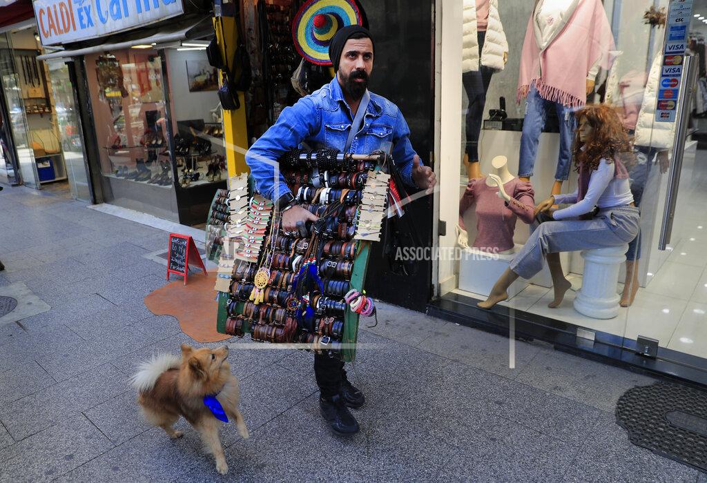Hussein Malla Ibrahim Farshoukh, 28, owner of a leather bracelets and bags shop, carries a stand with his products, on Beirut's commercial Hamra Street, in Beirut, Lebanon, Tuesday, March 16, 2021. More than half the population now lives in poverty, while an intractable political crisis heralds further collapse and Lebanese are gripped by fear for the future. (AP Photo/Hussein Malla)