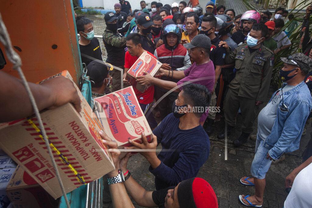 Yusuf Wahil People who are affected by an earthquake queue up for food aid in Mamuju, West Sulawesi, Indonesia, Sunday, Jan. 17, 2021. Rescuers retrieved more bodies from the rubble of homes and buildings toppled by the magnitude 6.2 earthquake while military engineers managed to reopen ruptured roads to clear access for relief goods. (AP Photo/Yusuf Wahil)