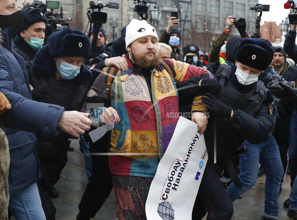 Pavel Golovkin Police detain a man during a protest against the jailing of opposition leader Alexei Navalny in Moscow, Russia, Saturday, Jan. 23, 2021. The man holds a poster reading: "Freedom for Navalny" and depicting a portrait of Russian President Vladimir Putin behind bars. Authorities in Russia have taken measures to curb protests planned for Saturday against the jailing of Navalny. (AP Photo/Pavel Golovkin)
