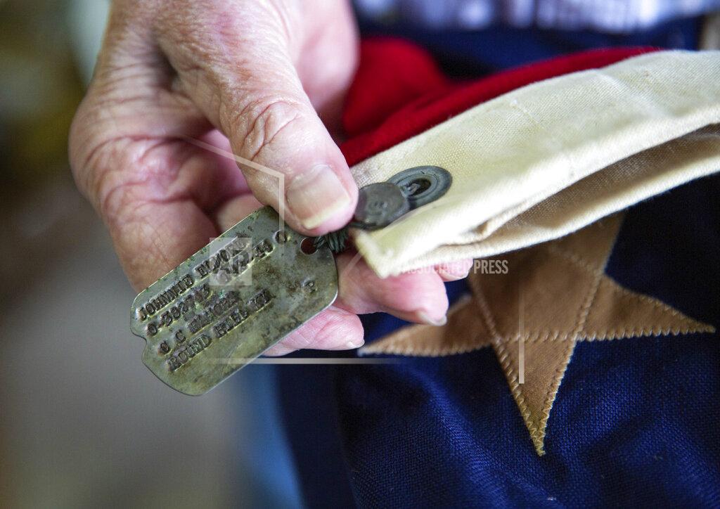 Grace Ramey Velda Alexander of Bowling Green, Ky., holds the dog tags of her father U.S. Army 2nd Lt. Johnnie Elmore which are tied to a folded American flag while going through the contents of his military footlocker trunk in her garage on Wednesday, Sept. 15, 2021, after she and her family found the trunk in her grandmother's old country store in Round Hill last week after it had been missing for nearly 77 years. Elmore, who graduated ROTC at Western Kentucky University in 1941, was killed in action in December 1944 at the age of 31 while based in France and England during World War II. The trunk contains a World War II uniform, a folded American flag, a Purple Heart and other medals and patches, dog tags, love letters to his soon-to-be wife Irene Martin, diaries and more. (Grace Ramey/Bowling Green Daily News via AP)/Daily News via AP)/Daily News via AP)