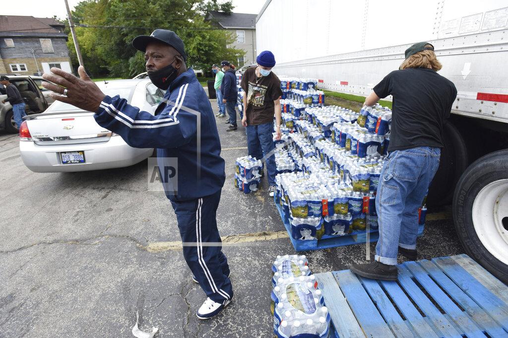 Don Campbell Dwayne Yarbrough directs traffic as volunteers distribute cases of bottled water to residents at God's Household of Faith, Friday, Oct. 15, 2021, in Benton Harbor, Mich. Gov. Gretchen Whitmer on Thursday ordered a “whole-of-government” response to elevated levels of lead in tap water in the southwestern Michigan city of Benton Harbor and vowed to accelerate the replacement of its lead pipes. (Don Campbell/The Herald-Palladium via AP)