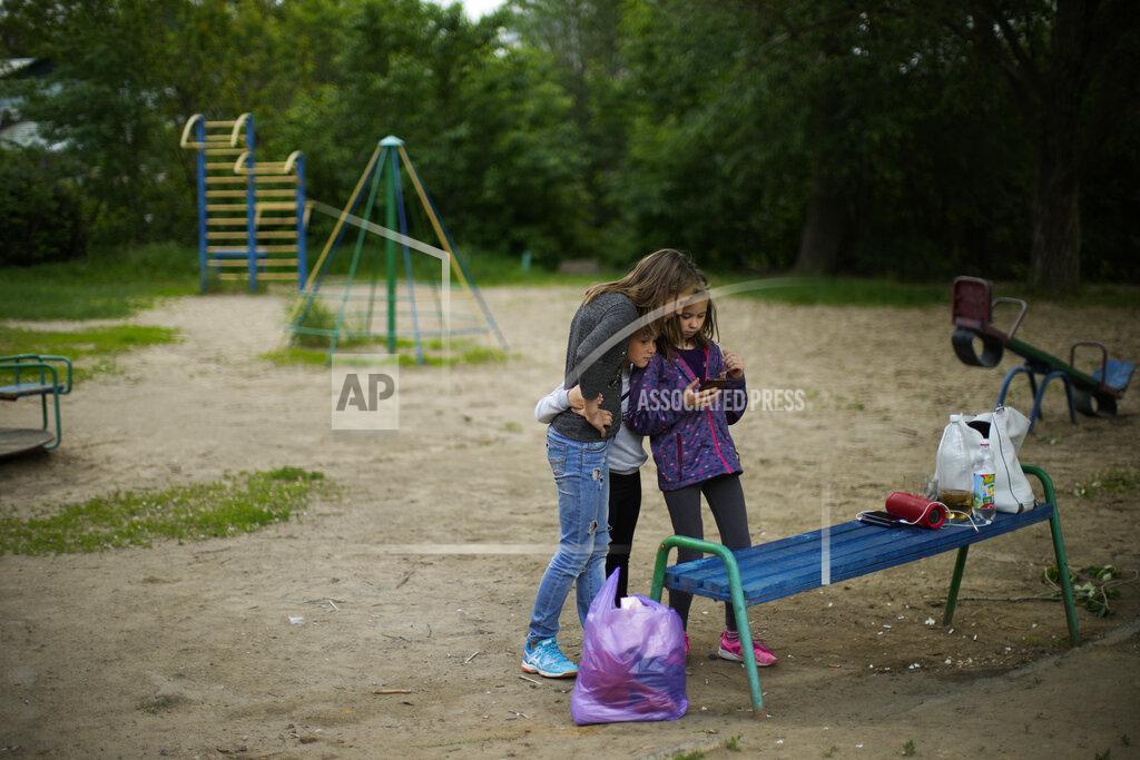 Francisco Seco Sisters Valeria, Sonya and Alina, from left, watch a music video in a cell phone in a children's playground near their home in Bakhmut, eastern Ukraine, Tuesday, May 24, 2022. (AP Photo/Francisco Seco)