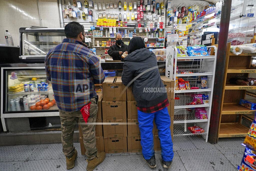 Kathy Willens Bodega owner Francisco Marte helps two customers Wednesday, Feb. 10, 2021, at his small grocery store in the Bronx borough of New York. Marte, president of the Bodega and Small Business Group, which represents bodegas in New York, has been lobbying local officials to set aside vaccine appointments for bodega workers, many of whom are unaware they are eligible. He hopes that the recent opening of a large vaccination site at Yankee stadium will make access easier. (AP Photo/Kathy Willens)