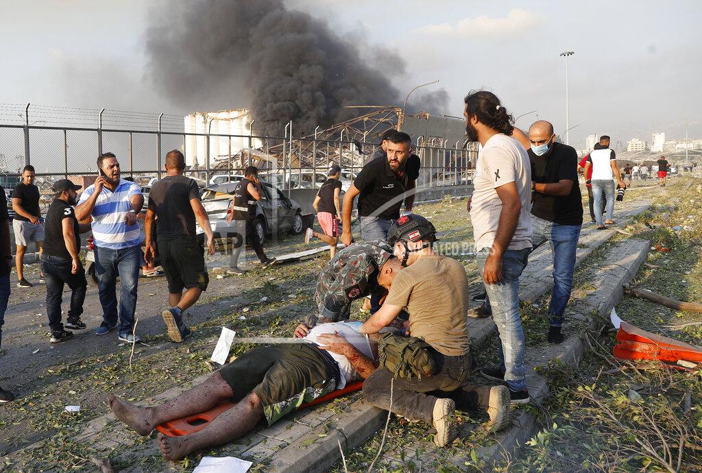 Hussein Malla EDS NOTE: GRAPHIC CONTENT - Rescue workers help an injured man at the explosion scene that hit the seaport of Beirut, Lebanon, Tuesday, Aug. 4, 2020. Massive explosions rocked downtown Beirut on Tuesday, flattening much of the port, damaging buildings and blowing out windows and doors as a giant mushroom cloud rose above the capital. Witnesses saw many people injured by flying glass and debris. (AP Photo/Hussein Malla)