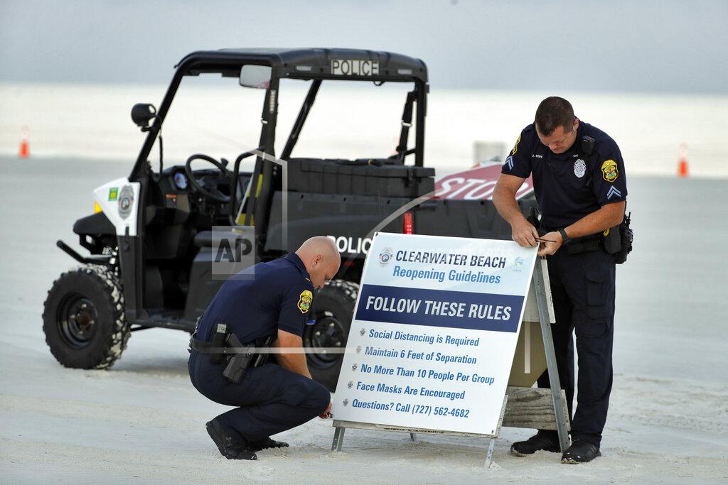 Chris O'meara Clearwater police officers Lt. Nate Burnside, left, and Cpl. Jarred Stiff put out beach rules signs on Clearwater Beach before it officially reopened to the public Monday, May 4, 2020, in Clearwater Beach, Fla. Many public beaches and restaurants are reopening as part of Florida Gov. Ron DeSantis' phase one to stop the spread of the coronavirus. (AP Photo/Chris O'Meara)