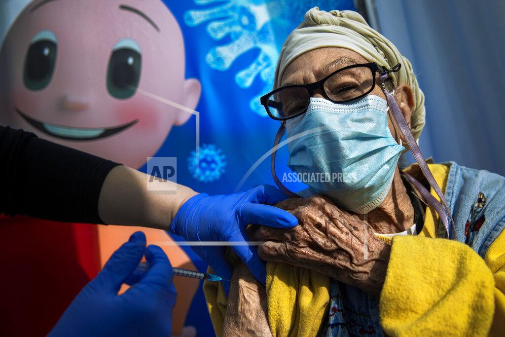 Oded Balilty A woman receives a coronavirus vaccine from medical staff at a COVID-19 vaccination center in Tel Aviv, Israel, Tuesday, Jan. 5, 2021. With elections approaching in March, Israeli Prime Minister Benjamin Netanyahu has placed his world-leading vaccination drive at the center of his re-election campaign launching an aggressive media blitz portraying him as almost singlehandedly leading the country out of the pandemic. (AP Photo/Oded Balilty)