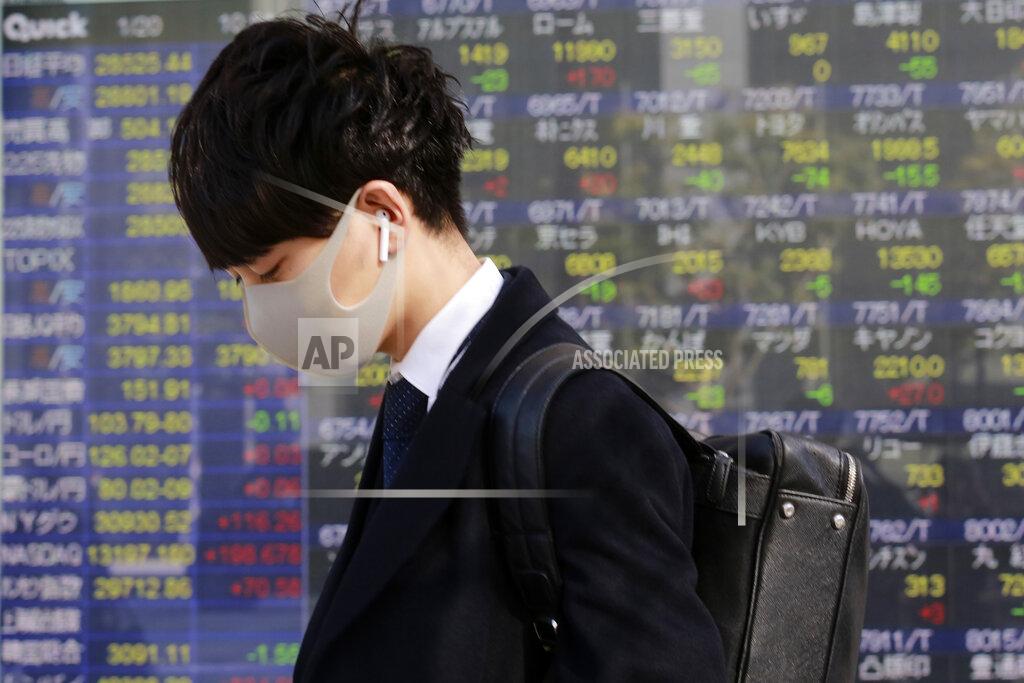 Koji Sasahara A man walks by an electronic stock board of a securities firm in Tokyo, Wednesday, Jan. 20, 2021. Asian shares were mostly higher Wednesday, ahead of Joe Biden's inauguration as president, ending President Donald Trump’s four-year term. Japan's benchmark lost early gains as worries grew about the surge in coronavirus cases. (AP Photo/Koji Sasahara)