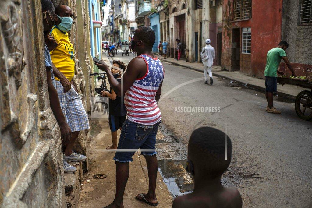 Ramon Espinosa FILE - In this Oct. 27, 2020 file photo wearing face masks amid the new coronavirus pandemic, residents visit in Havana, Cuba, one wearing a shirt with an American flag motif. While Joe Biden was part of an administration that reestablished diplomatic ties with Cuba, loosened travel restrictions and made it easier for Cubans in the United States to send money home, President Donald Trump has increased sanctions on companies that do business with the island's government and even banned Americans from staying in Cuban state-owned hotels. (AP Photo/Ramon Espinosa, File)