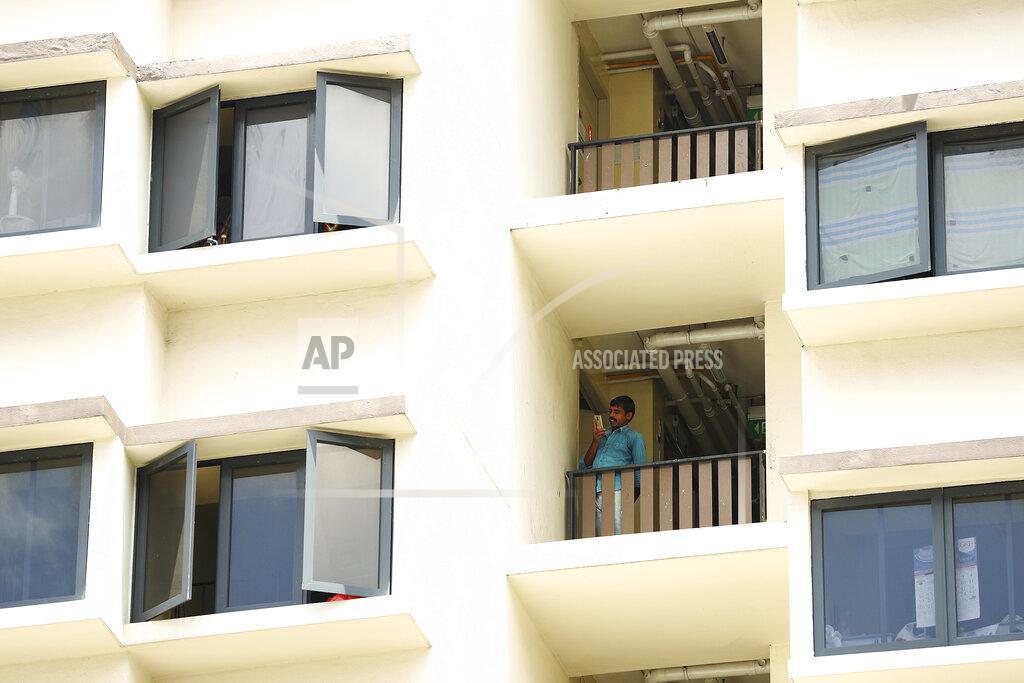 Yong Teck Lim FILE - In this April 10, 2020, file photo, a foreign worker talks on the phone outside his room at the WestLite Toh Guan dormitory after it was declared an isolation area under the Infectious Diseases Act, following a spike in the number of COVID-19 cases in several foreign worker dormitories in Singapore. A second wave of coronavirus infections in tightly packed foreign workers' dormitories has caught Singapore off guard, and exposed the danger of overlooking marginal groups in a health crisis. Infections in Singapore, an affluent Southeast Asian city-state of fewer than 6 million people, have jumped more than a hundredfold in two months — from 226 in mid-March to over 23,000, the most in Asia after China and India.(AP Photo/Yong Teck Lim, File)