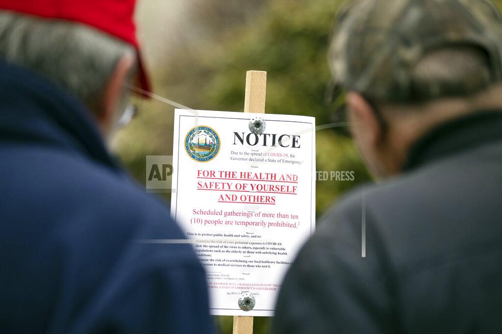 Michael Dwyer Tom Ploszaj, left, and Tony Stelik read a sign prohibiting gatherings of 10 or more people as they arrive at the State House for a scheduled protest against the state lockdown due to COVID-19, Saturday, April 18, 2020, in Concord, N.H. (AP Photo/Michael Dwyer)