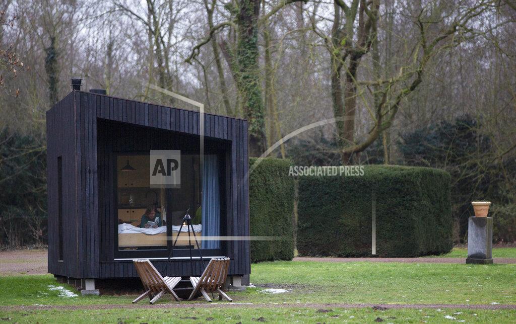 Virginia Mayo Kim Devos reads a book in a Slow Cabin in Elewijt, Belgium, Monday, Feb. 15, 2021. These Slow Cabins, set up the Belgian countryside, are the new way to vacation in pandemic times: in complete solitude and in the middle of nowhere. The wooden cabins are fully sustainable, provided you don't stay in the shower too long and you can live without Wi-Fi. (AP Photo/Virginia Mayo)