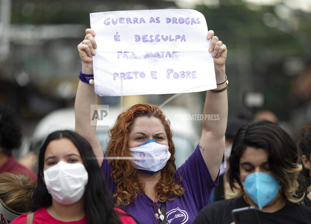Silvia Izquierdo A woman holds a sign that reads in Portuguese: "The war on drugs is an excuse to kill black and poor people" after a deadly police operation in the Jacarezinho favela of Rio de Janeiro, Brazil, Friday, May 7, 2021. A bloody, hours-long gunbattle here echoed into Friday, with authorities saying the police mission killed two dozen criminals while residents and activists claimed human rights abuses. (AP Photo/Silvia Izquierdo)