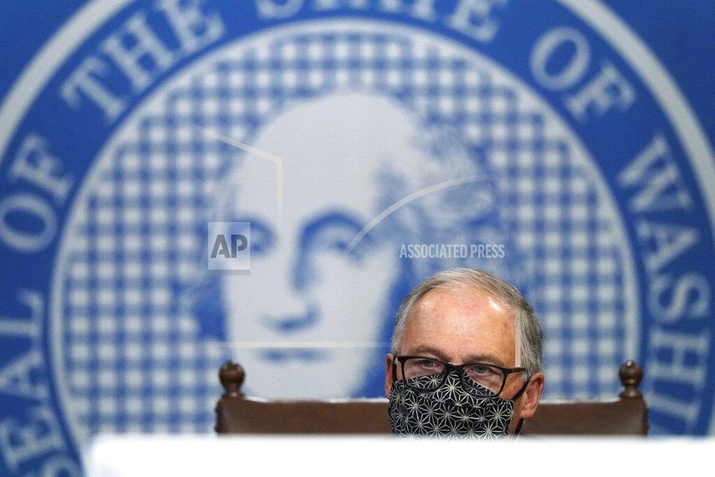 Washington Gov. Jay Inslee speaks behind a video conference streaming device during a news conference, Monday, Nov. 30, 2020, at the Capitol in Olympia, Wash. The state announced a new statewide coronavirus exposure notification program Monday that uses smartphone technology in the ongoing effort to prevent the spread of COVID-19. People with Apple iPhones can now enable the 'exposure notifications' feature that is already in their phone's settings, and Android devices can download the app. Use of the service is voluntary and users can opt-out at any time. (AP Photo/Ted S. Warren)
