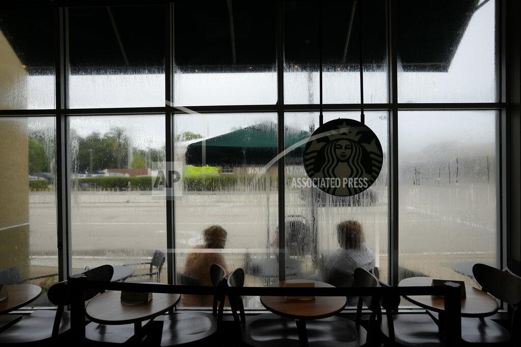 Rebecca Blackwell Krystina Francois, left, and Francesca Menes, children of Haitian immigrants to the U.S. and co-founders of the Black Collective, are seen through windows streaked from a recent rain, as they work together outside a Starbucks, Tuesday, Sept. 21, 2021, in Miami Shores, Fla. Menes and Francois, whose advocacy organization focuses on the political needs and economic empowerment of Black people across the African diaspora, have called for the Biden administration to immediately suspend plans to remove migrants via planes bound for Haiti. (AP Photo/Rebecca Blackwell)