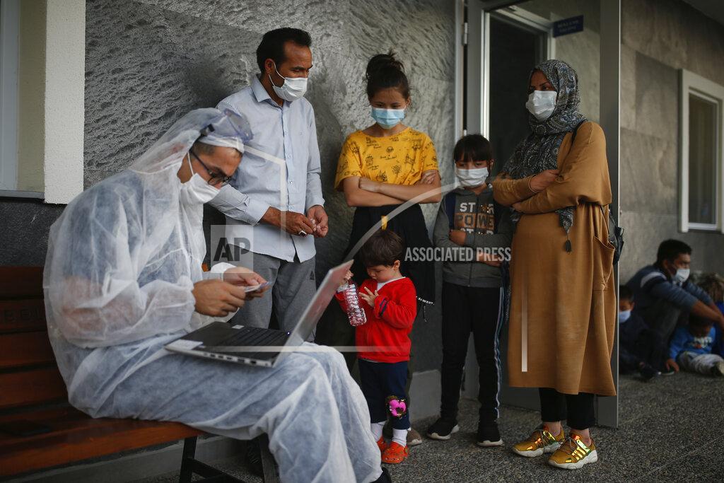 Emrah Gurel A Turkish coast guard officer at Dikili, Turkey, wearing protective gear to help prevent the spread of coronavirus, registers migrants after they were rescued in the Aegean Sea, between Turkey and Greece, Saturday, Sept. 12, 2020. Turkey is accusing Greece of large-scale pushbacks at sea — summary deportations without access to asylum procedures, in violation of international law. The Turkish coast guard says it rescued over 300 migrants "pushed back by Greek elements to Turkish waters" this month alone. Greece denies the allegations and accuses Ankara of weaponizing migrants. (AP Photo/Emrah Gurel)
