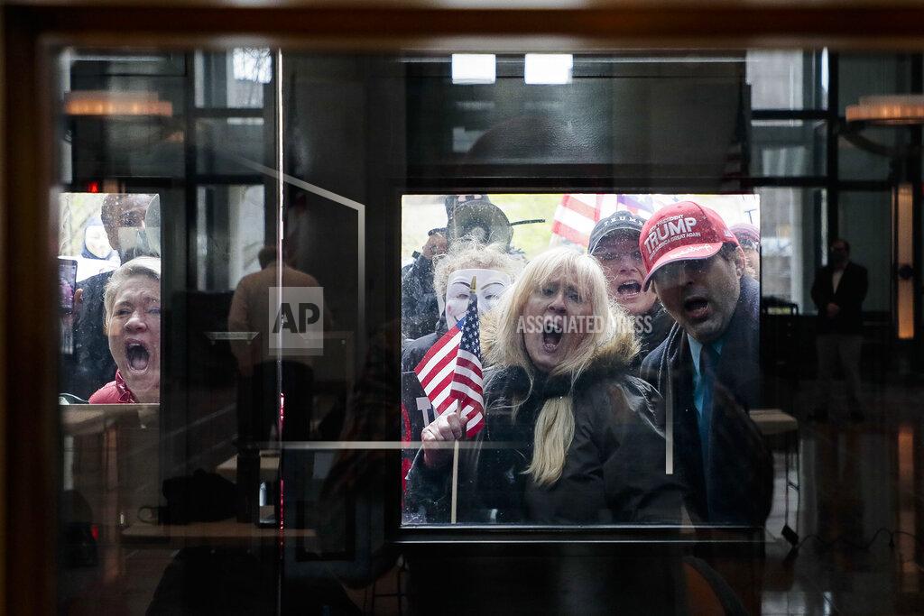 Joshua A. Bickel FILE - In this April 13, 2020, file photo Ohio state senate candidate Melissa Ackison, left, and other protesters stand outside the Statehouse Atrium where reporters listen during the State of Ohio's Coronavirus response update at the Ohio Statehouse in Columbus, Ohio. The unprecedented national effort to shut down much of daily life to slow the spread of COVID-19 is prompting a growing number of protests. (Joshua A. Bickel/The Columbus Dispatch via AP, File)