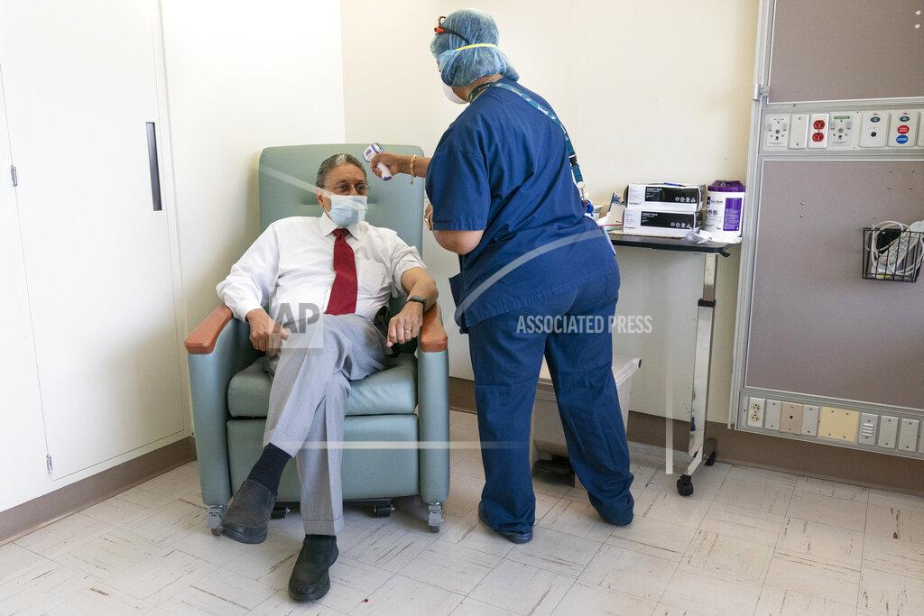 Jacquelyn Martin In this Wednesday, Feb. 10, 2021, photo Wallace Charles Smith, 72, who is a pastor at Shiloh Baptist Church, has his temperature taken before receiving his first COVID-19 vaccination by nurse Michelle Martin at United Medical Center in southeast Washington. (AP Photo/Jacquelyn Martin)