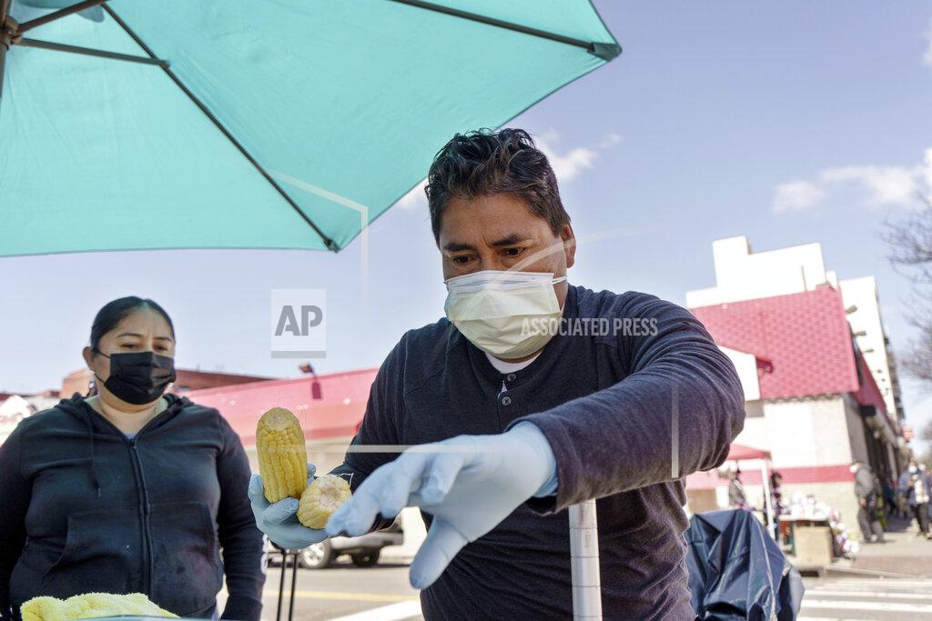 Marshall Ritzel Ruth Palacios and Arturo Xelo, a married couple from Mexico, work at their fruit stand in the Corona neighborhood of the Queens borough of New York on Tuesday, April 13, 2021. They worked seven days a week for months disinfecting COVID-19 patient rooms at the Memorial Sloan Kettering Cancer Center in New York City, but weren't paid overtime Palacios says. The couple filed a federal lawsuit against the contractor that hired them, alleging their pay was cut without their knowledge from $15 an hour to $12.25. They're now selling fruit to make ends meet. (AP Photo/Marshall Ritzel)