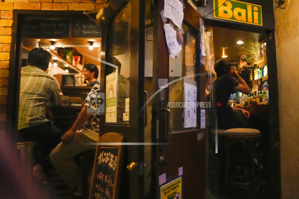 People gather at bars after government imposed 8 p.m. closing time for restaurants and bars under Tokyo's fourth state of emergency Saturday, July 17, 2021, in Tokyo. The latest state of emergency has asked restaurants and bars to close by 8 p.m., if not entirely. This has pushed people to drink outside, although many bars remain open and bustling with customers who are defying the rules and expressing frustration and indifference. (AP Photo/Kiichiro Sato)