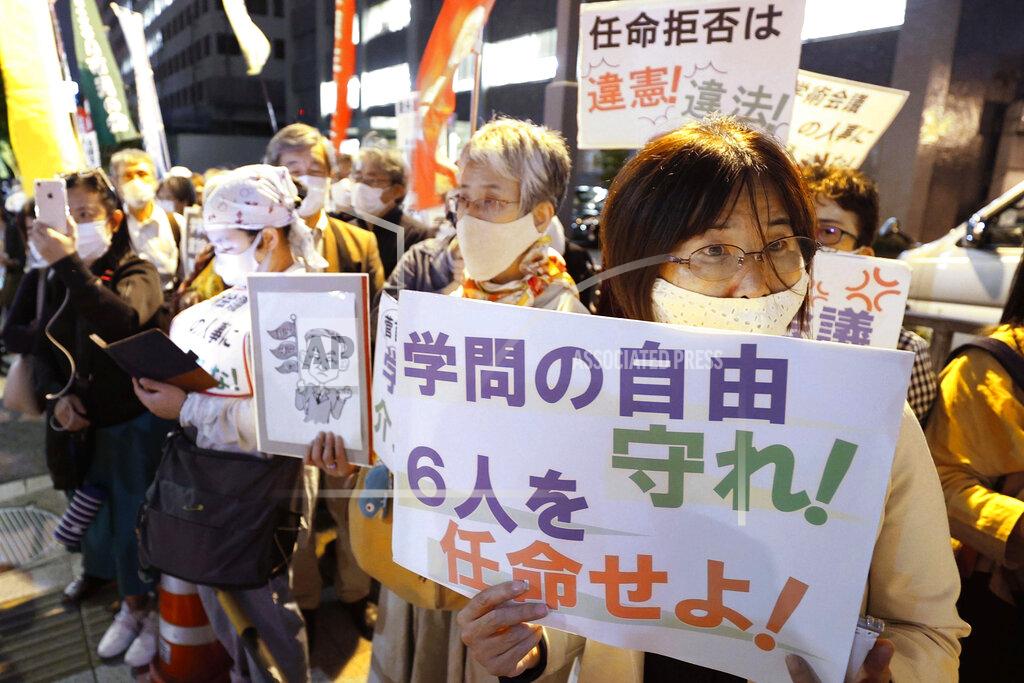 Uncredited People gather outside the prime minister's office in Tokyo on Oct. 6, 2020, during a protest against Japanese Prime Minister Yoshihide Suga's refusal, without explanation, to approve the appointments of six scholars to a government advisory body. This has drawn accusations that Suga is trying to muzzle dissent and impinge on academic freedoms. A sign, bottom right, reads "Protect academic freedoms. Appoint the six scholars." (Kyodo News via AP)