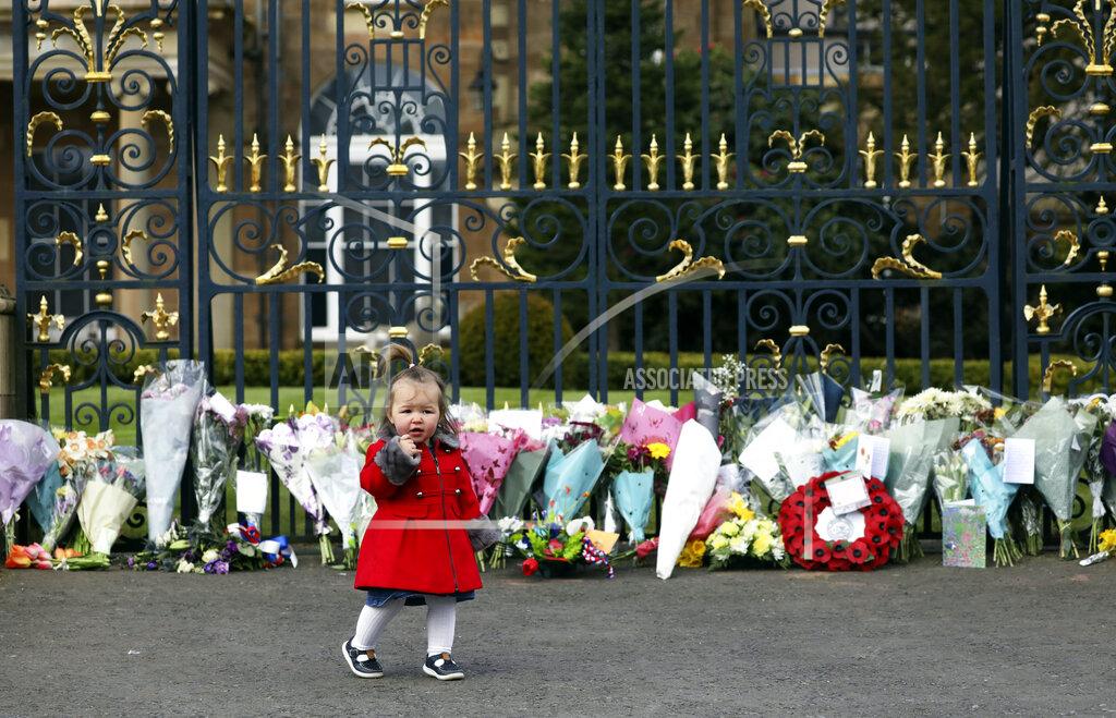 Peter Morrison Maisie Cairns (18 months) stands at the gates of Hillsborough Castle in Belfast, Northern Ireland, Saturday, April 10, 2021. People gathered to pay respect to Britain's Prince Philip who died early Friday. Prince Philip, the irascible and tough-minded husband of Queen Elizabeth II who spent more than seven decades supporting his wife in a role that both defined and constricted his life. (AP Photo/Peter Morrison)