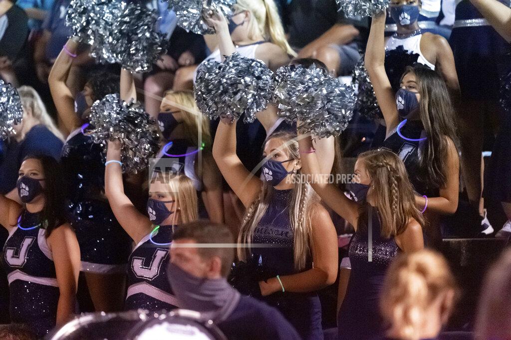 Vasha Hunt FILE - In this Aug. 20, 2020, file photo, the Jemison band's flag girls wear masks as they cheer on their team at an Alabama high school football game between Jemison and Thorsby in Thorsby, Ala. A football-starved nation is getting its games back with the start of the NFL season, but many worry that attending games or get-togethers will lead to a new surge in coronavirus infections. Many high schools have started football but states like California and Illinois canceled the entire season. (AP Photo/Vasha Hunt, File)