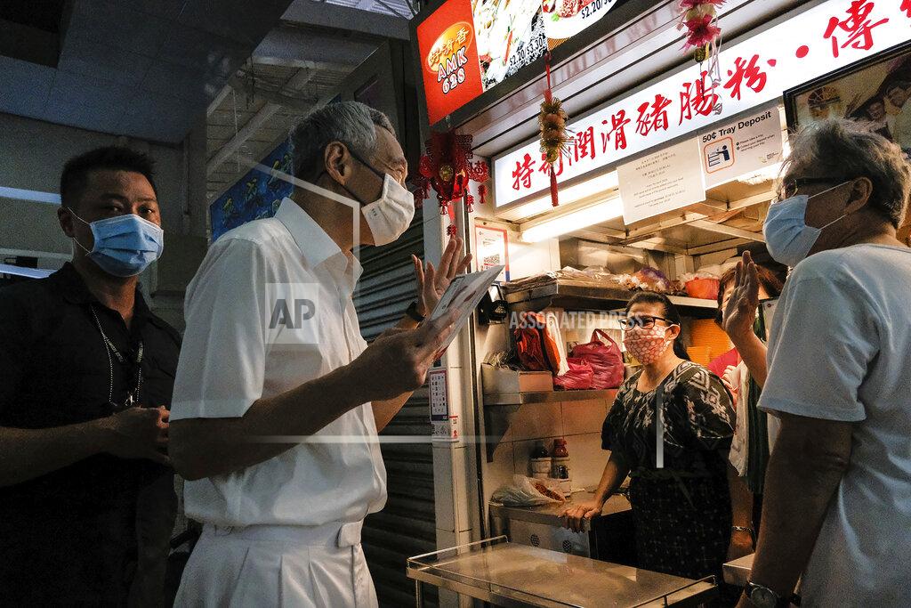 Ee Ming Toh Singapore Prime Minister and Secretary-General of the People's Action Party Lee Hsien Loong, second left, wears a face mask while talking to food vendors at a local market at Yio Chu Kang while on the campaign trail in Singapore July 3, 2020. Singaporeans go to the polls on July 10 in Southeast Asia's first election since the coronavirus pandemic began, with the health crisis and an economic recession expected to bolster Prime Minister Lee's party and extend its unbroken rule. (AP Photo/Ee Ming Toh)