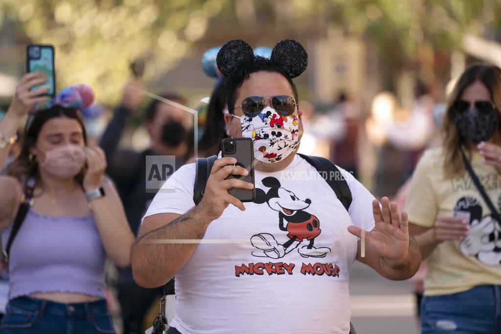 Jae C. Hong FILE - In this April 30, 2021, file photo, guests walk along the Main Street USA at Disneyland in Anaheim, Calif. Los Angeles and San Francisco are reopening more businesses under California's least restrictive coronavirus safety rules, even though they have more infections than many other big counties, state data shows. (AP Photo/Jae C. Hong, File)