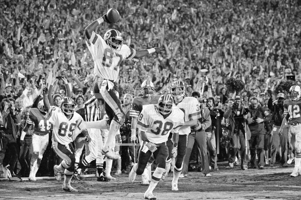 Uncredited FILE - In this Jan. 30, 1983, file photo, Washington Redskins receiver Charlie Brown (87) gets ready to spike the ball after he scored a fourth quarter touchdown against the Miami Dolphins in Super Bowl XVII in Pasadena, Calif. Coming over to congratulate Brown are teammates Alvin Garrett (89) and Clarence Harmon (38). The Redskins won 27-17. (AP Photo/File)