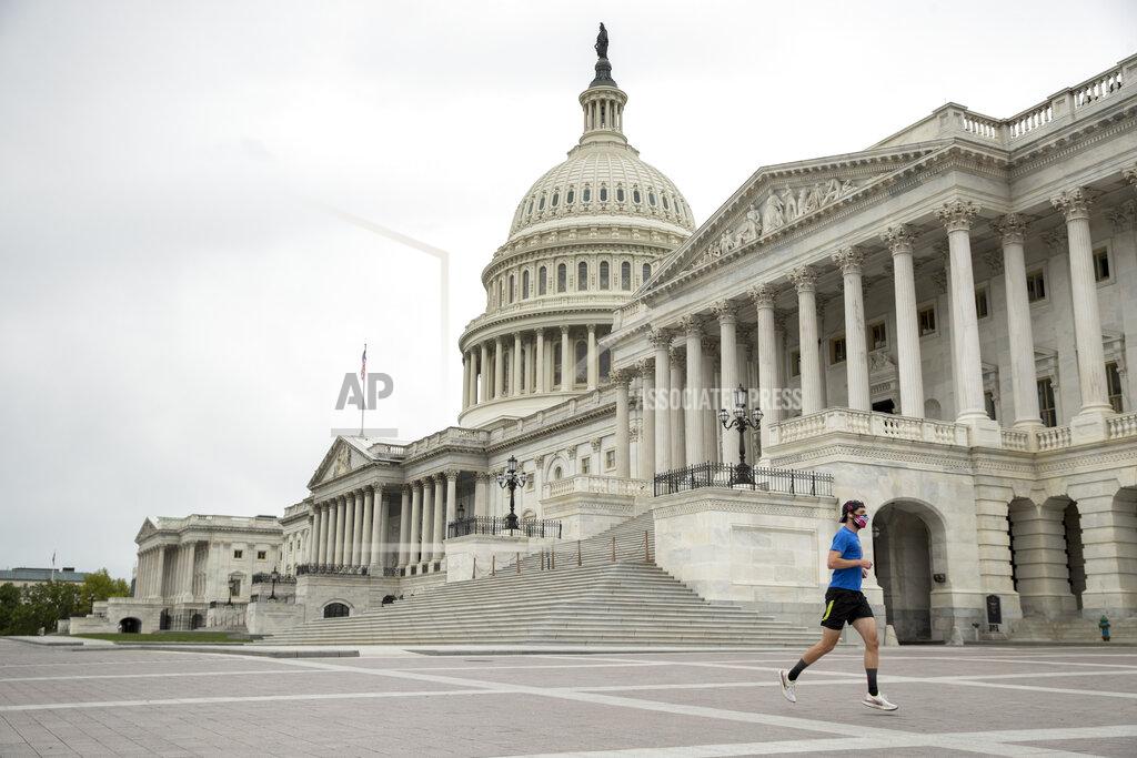 Andrew Harnik A man wearing a mask depicting American flags jogs past the U.S. Capitol Building, Tuesday, April 28, 2020, in Washington. The U.S. House of Representatives has canceled plans to return next week, a reversal after announcing it a day earlier. (AP Photo/Andrew Harnik)