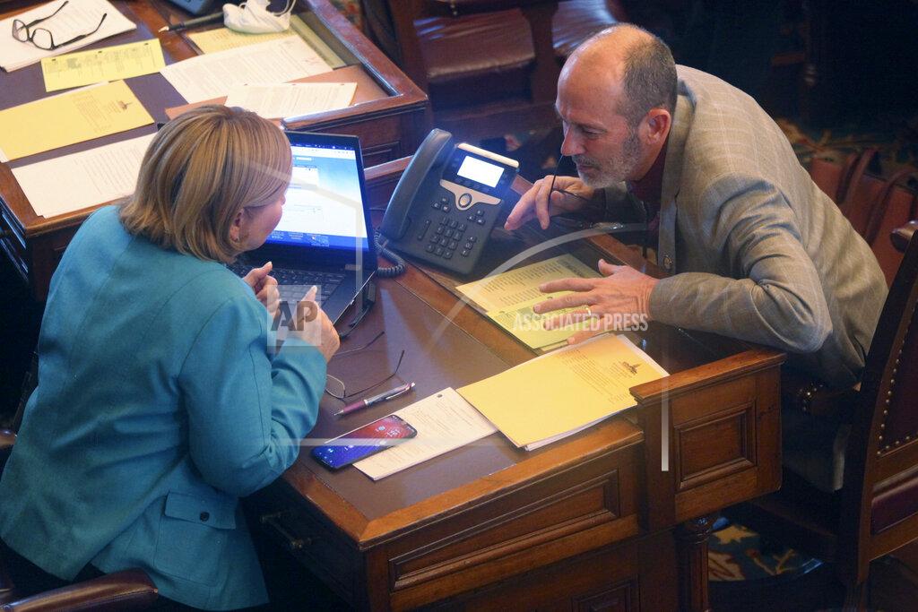 John Hanna In this photo from Thursday, Feb. 4, 2021, Kansas state Sens. Caryn Tyson, left, R-Parker, and Mark Steffen, right, R-Hutchinson, confer during the Senate's debate on a resolution condemning Democratic Gov. Laura Kelly's policy of making prison inmates eligible for COVID-19 vaccines now, at the Statehouse in Topeka, Kan. Both voted for the resolution, which has passed. (AP Photo/John Hanna)