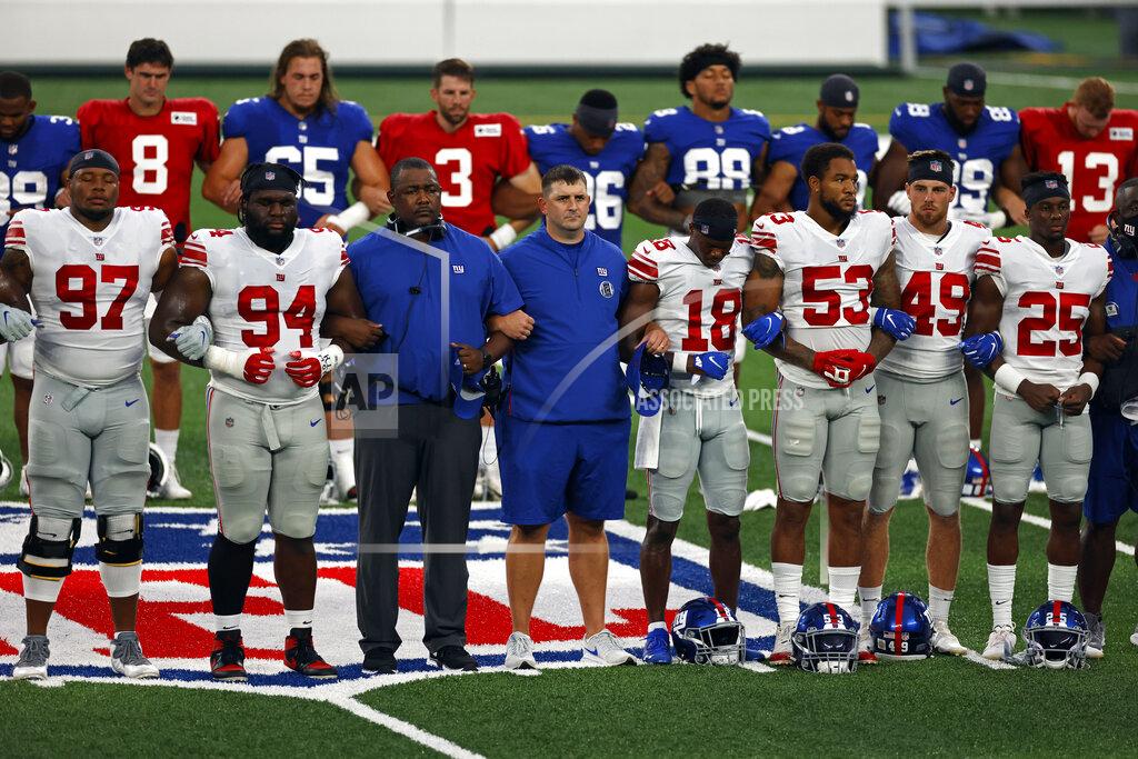 FILE - New York Giants head coach Joe Judge, center, stands with arms linked with his players to make a social injustice statement prior to their scrimmage at the NFL football team's training camp in East Rutherford, N.J., Friday, Aug. 28, 2020. A long-time advocate of the right to protest for social change and equality, New York Giants co-owner John Mara admits he was stunned listening to his players talk about their experiences with police and authorities in the wake of the death George Floyd in June. (AP Photo/Adam Hunger, File)