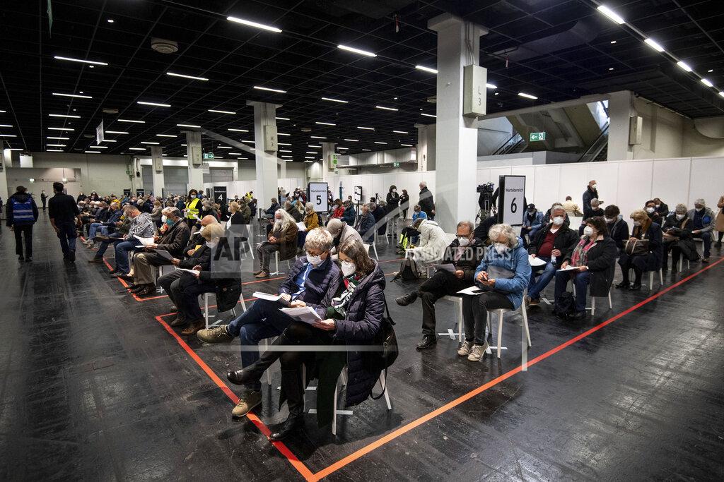 Marius Becker People wait with mouth-to-nose coverage in a vaccination center in Cologne, Germany, Sunday, April 4, 2021. In North Rhine-Westphalia, people aged 60 and over have been able to get vaccinated against the coronavirus with the active ingredient from Astrazeneca since this weekend. The rush for the vaccination appointments for the age group 60 plus had already led to overloaded lines on the phone and on the Internet in the early morning of Holy Saturday, 03.04.2021. (Marius Becker/dpa via AP)