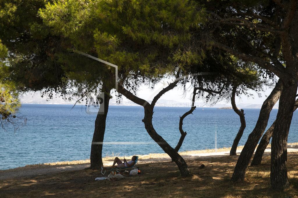 Yorgos Karahalis A man reads a book as he lies on a sun bed under pines at Varkiza village, a few miles southwest of Athens, on Thursday, July 29, 2021. One of the most severe heat waves recorded since 1980s scorched southeast Europe on Thursday, sending residents flocking to the coast, public fountains and air-conditioned locations to find some relief, with temperatures rose above 40 C (104 F) in parts of Greece and across much of the region. (AP Photo/Yorgos Karahalis)