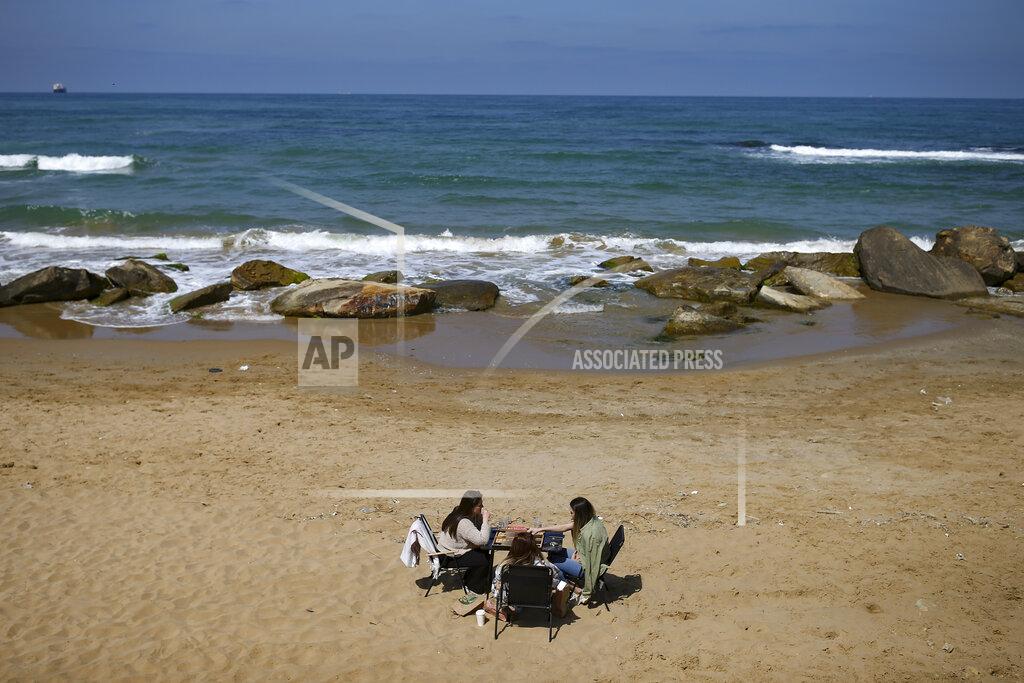 Emrah Gurel People sit on the beach in Kilyos, northern Istanbul, Thursday, April 29, 2021, a few hours before the start of the latest lockdown to help protect from the spread of the coronavirus. People stocked up on groceries, shoppers filled markets and many left cities for their hometowns or the southern coast as Turkey's strictest COVID-19 lockdown yet came into effect late Thursday. President Recep Tayyip Erdogan imposed a "full lockdown" until May 17 amid soaring COVID-19 infections and deaths. Turkey now ranks among the world's worst-hit countries and it's the first time that it is imposing a nearly three-week lockdown for the whole of the country. (AP Photo/Emrah Gurel)
