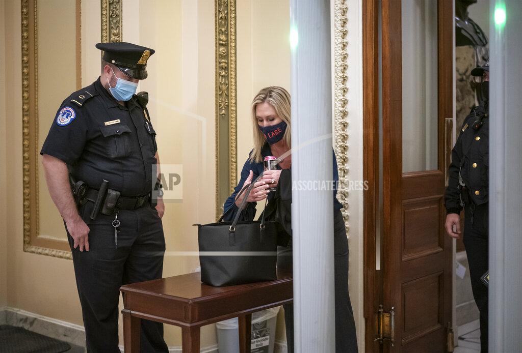 J. Scott Applewhite Rep. Marjorie Taylor Greene, R-Ga., an ally of President Donald Trump, passes through a metal detector before entering the House chamber, a new security measure put into place after a mob stormed the Capitol, in Washington, Tuesday, Jan. 12, 2021. The House is trying to push the vice president and Cabinet to act even more quickly to remove President Donald Trump from office. Democrats are set to pass a resolution calling on Vice President Mike Pence to invoke constitutional authority under the 25th Amendment to oust Trump. (AP Photo/J. Scott Applewhite)